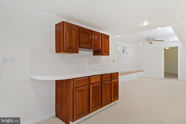 kitchen featuring backsplash, baseboards, ceiling fan, light colored carpet, and a sink