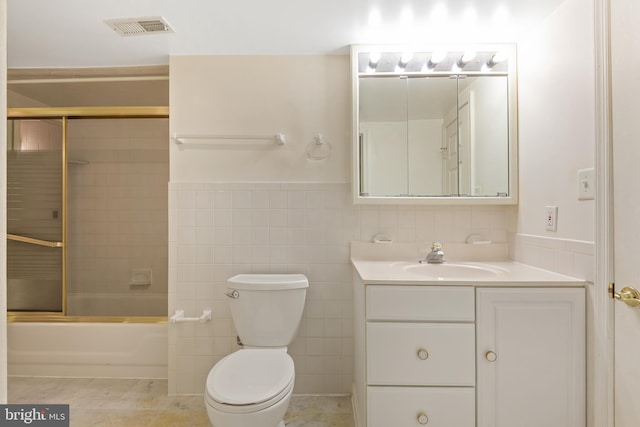 bathroom with visible vents, toilet, tile walls, wainscoting, and vanity