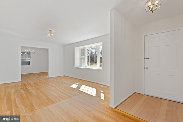 foyer entrance featuring an inviting chandelier, wood finished floors, visible vents, and baseboards