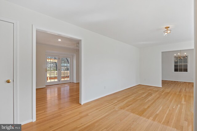 empty room featuring baseboards, light wood-style floors, and an inviting chandelier