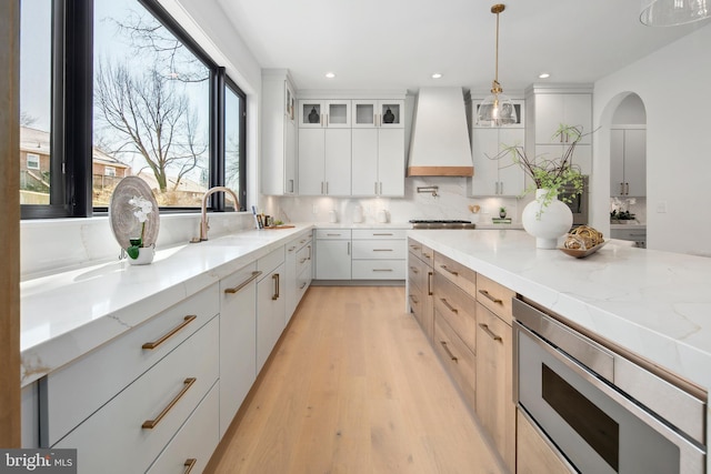 kitchen with a sink, premium range hood, appliances with stainless steel finishes, and backsplash