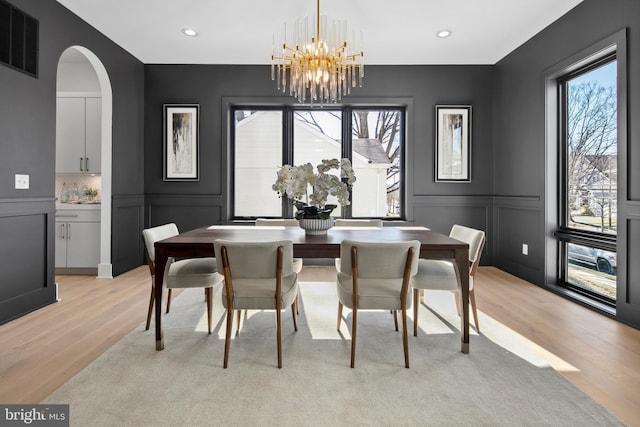 dining area with a healthy amount of sunlight, light wood finished floors, visible vents, and a decorative wall