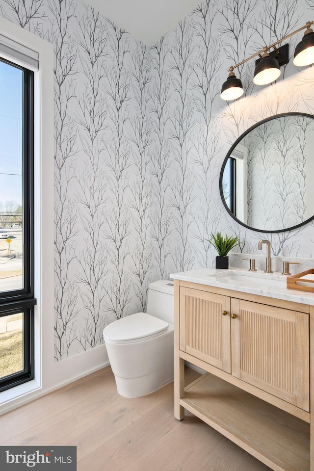 bathroom featuring wood finished floors, vanity, toilet, and wallpapered walls