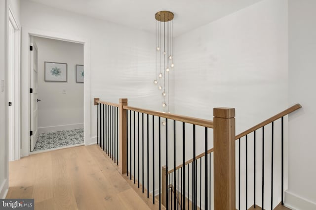 hallway with baseboards, an upstairs landing, and wood finished floors