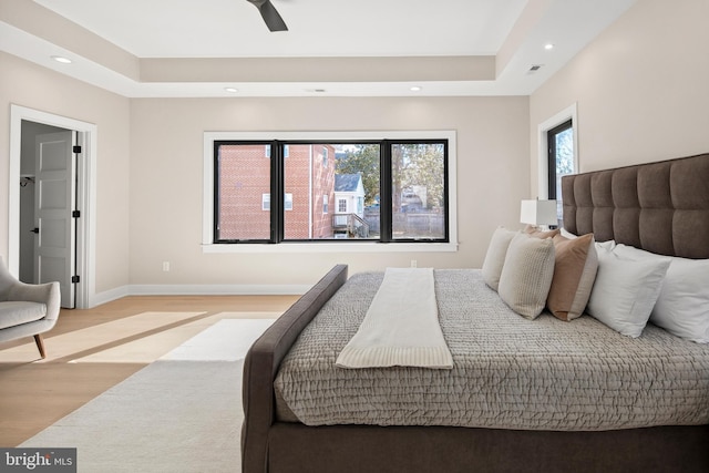 bedroom featuring a tray ceiling, recessed lighting, visible vents, light wood-style floors, and baseboards