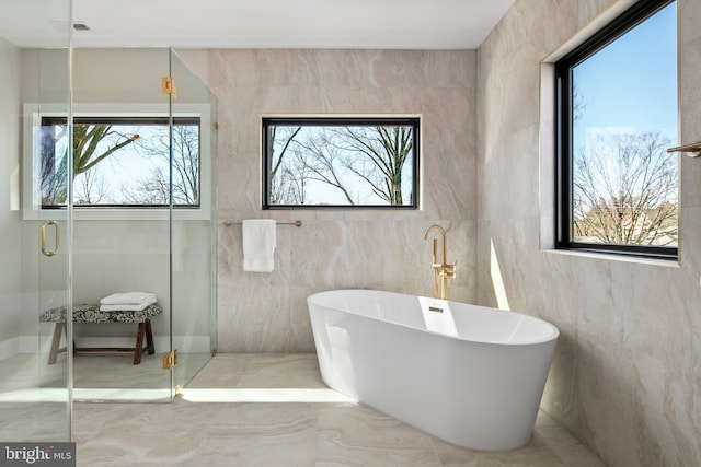 bathroom with a stall shower, a soaking tub, and plenty of natural light