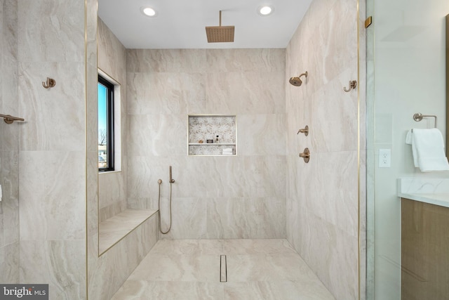 bathroom with recessed lighting, a tile shower, and vanity