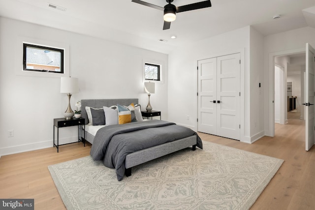 bedroom with a closet, baseboards, visible vents, and light wood finished floors