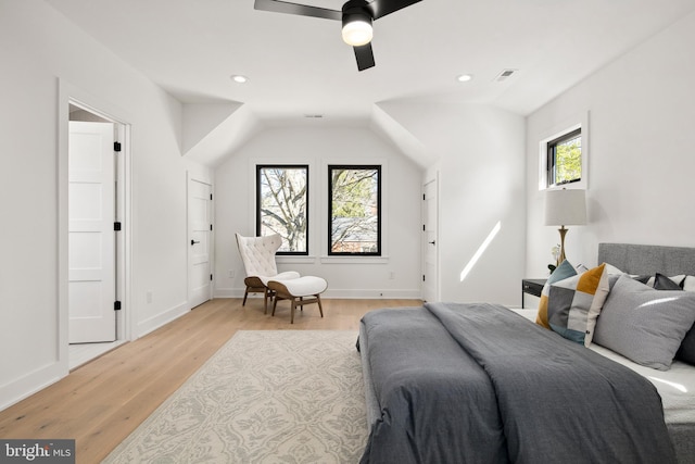 bedroom featuring light wood-style floors, baseboards, visible vents, and vaulted ceiling