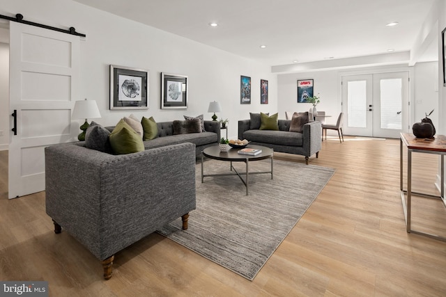 living room featuring french doors, a barn door, recessed lighting, and light wood-style floors