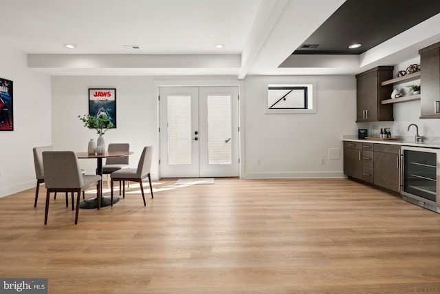 dining area with light wood finished floors, beverage cooler, baseboards, wet bar, and french doors