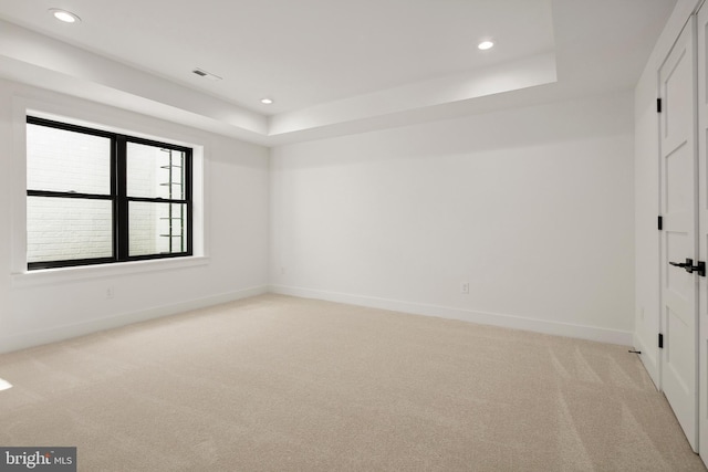 unfurnished room with recessed lighting, baseboards, a tray ceiling, and light colored carpet