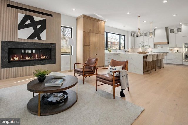 living room featuring recessed lighting, a glass covered fireplace, and light wood finished floors