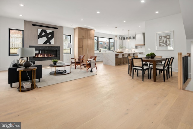 dining area featuring light wood finished floors, baseboards, a multi sided fireplace, and recessed lighting