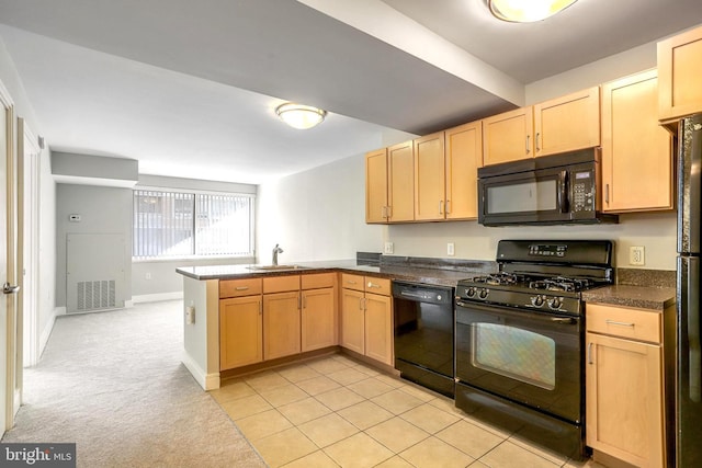 kitchen featuring visible vents, a peninsula, light brown cabinetry, black appliances, and a sink