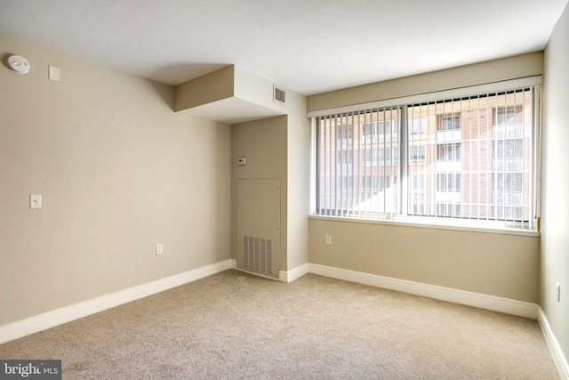 unfurnished room with a healthy amount of sunlight, visible vents, and light colored carpet