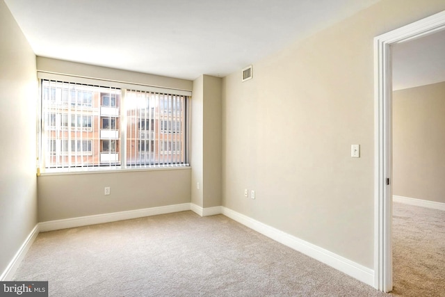 empty room featuring carpet, visible vents, and baseboards