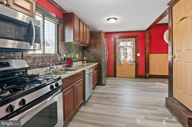 kitchen with appliances with stainless steel finishes, plenty of natural light, a sink, and light wood-style flooring