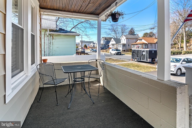 balcony featuring a sunroom, a residential view, and a porch