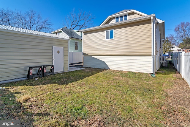 rear view of house with an outbuilding, a yard, and fence