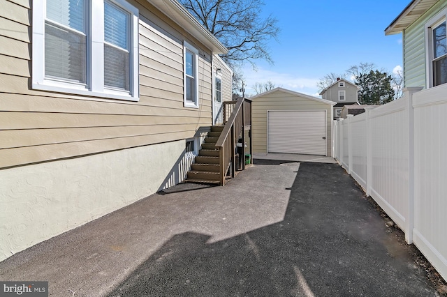 view of side of home featuring a garage, fence, an outdoor structure, and aphalt driveway