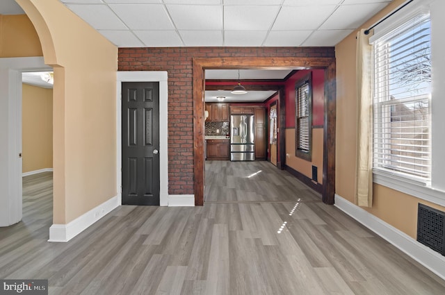 foyer entrance with baseboards, a drop ceiling, visible vents, and light wood-style floors