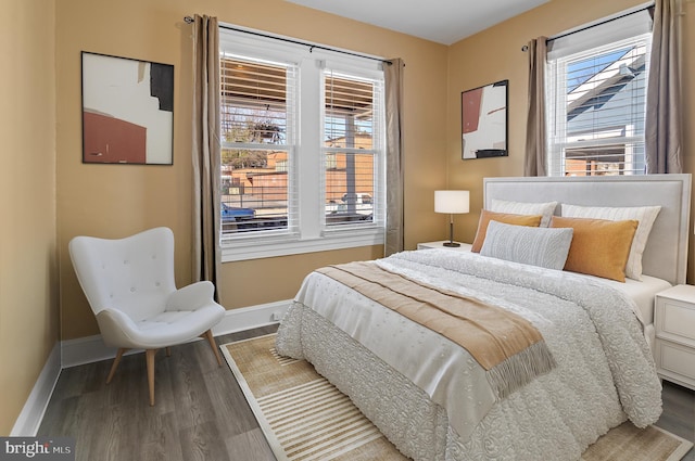 bedroom with multiple windows, wood finished floors, and baseboards