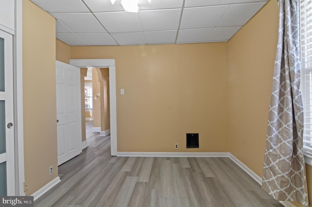 spare room featuring a drop ceiling, wood finished floors, and baseboards