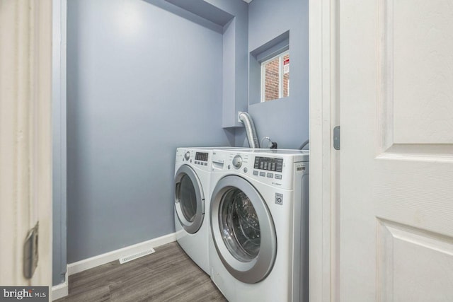 laundry area featuring visible vents, washer and clothes dryer, baseboards, and wood finished floors