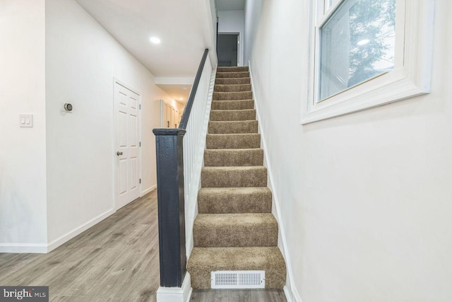 stairway with visible vents, baseboards, and wood finished floors