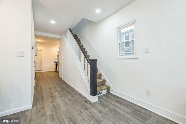 stairway with wood finished floors, visible vents, and baseboards