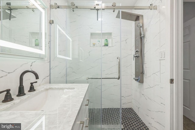 full bathroom with a marble finish shower and vanity