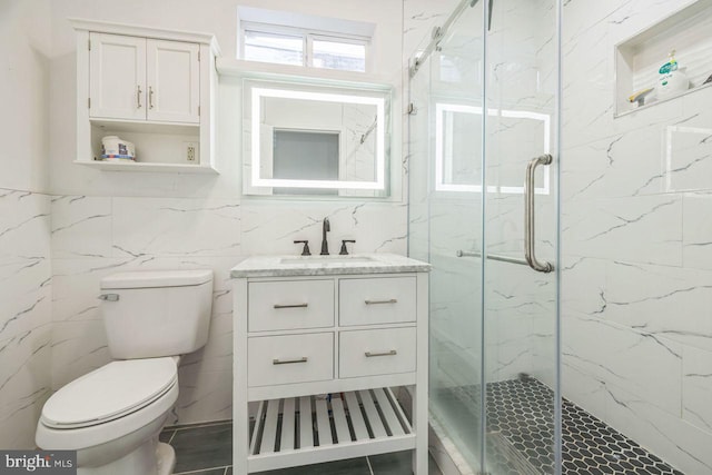 bathroom with tile walls, toilet, vanity, and a marble finish shower