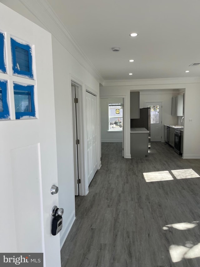 hall featuring recessed lighting, dark wood-type flooring, visible vents, baseboards, and ornamental molding