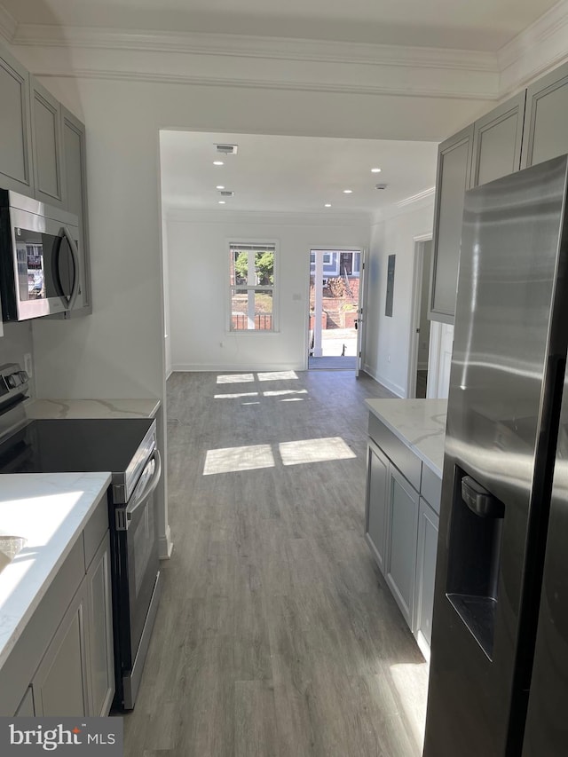 kitchen featuring ornamental molding, appliances with stainless steel finishes, gray cabinets, and light wood-style flooring