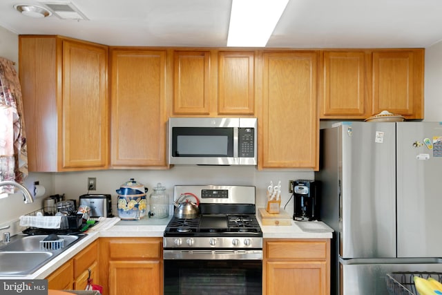 kitchen featuring appliances with stainless steel finishes, light countertops, a sink, and visible vents