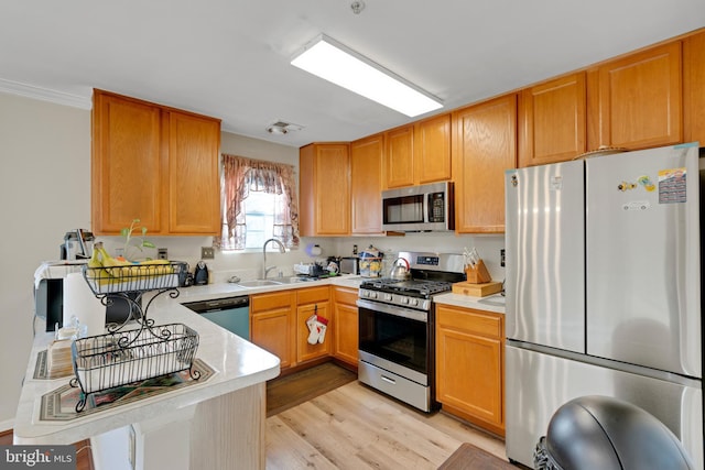 kitchen featuring stainless steel appliances, a sink, visible vents, light countertops, and light wood finished floors