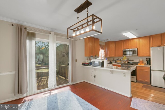 kitchen with a peninsula, visible vents, light countertops, appliances with stainless steel finishes, and light wood finished floors