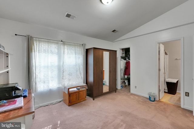 bedroom featuring a walk in closet, visible vents, vaulted ceiling, and light colored carpet