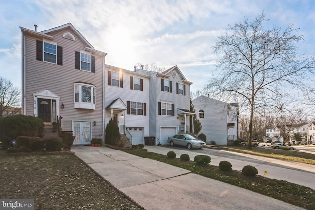 view of property with concrete driveway, an attached garage, and a residential view