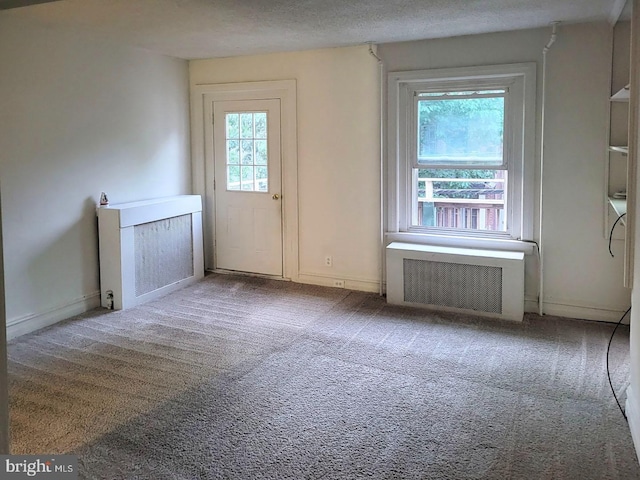 interior space featuring a textured ceiling, radiator heating unit, and baseboards