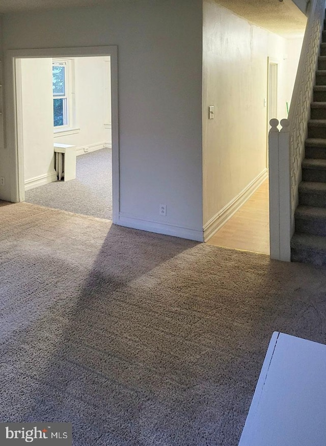 carpeted spare room with stairway and baseboards