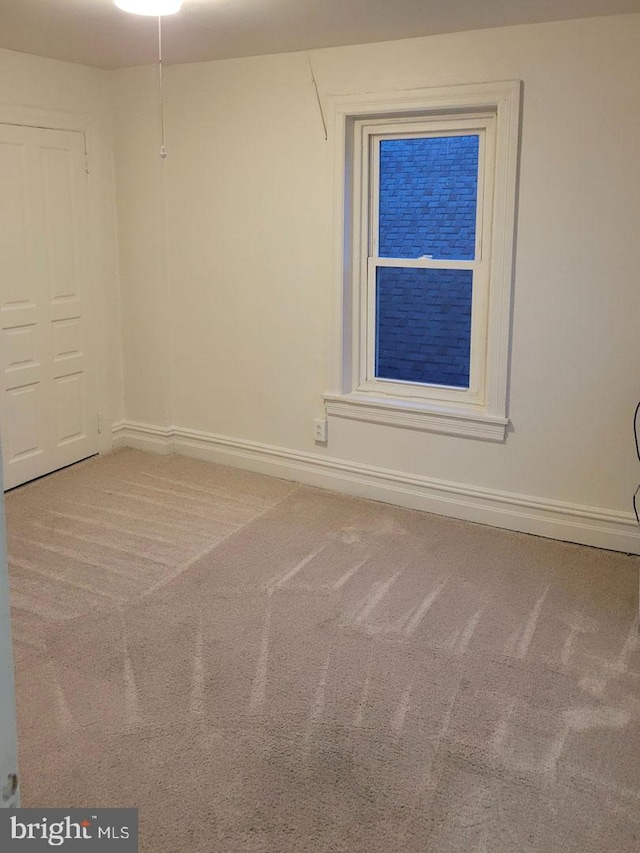 empty room featuring carpet and baseboards