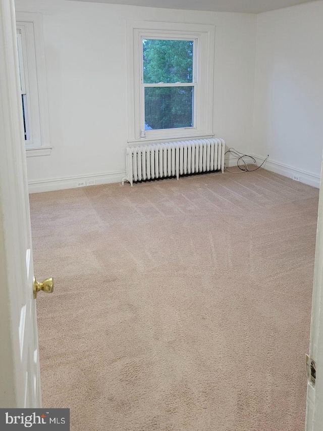 empty room with baseboards, carpet, and radiator