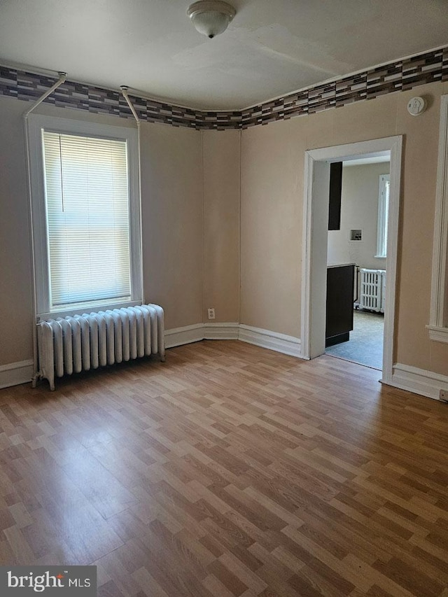 unfurnished room with radiator heating unit and wood finished floors