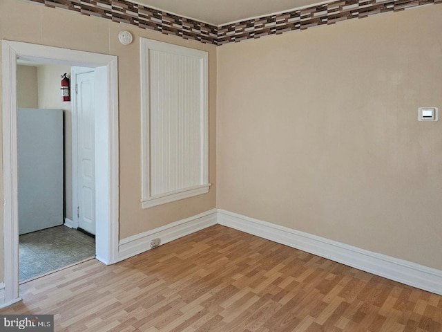 spare room with baseboards and light wood finished floors