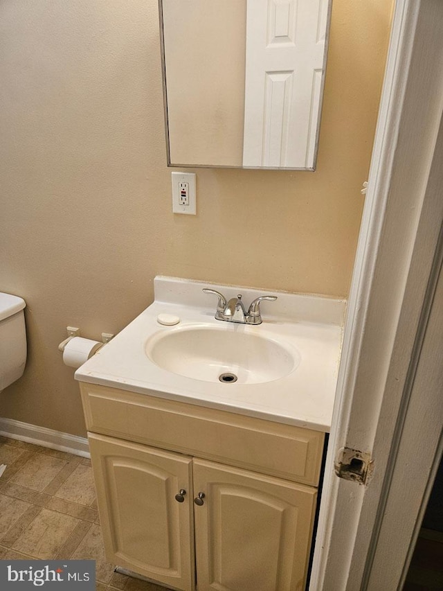 bathroom featuring vanity, toilet, and baseboards