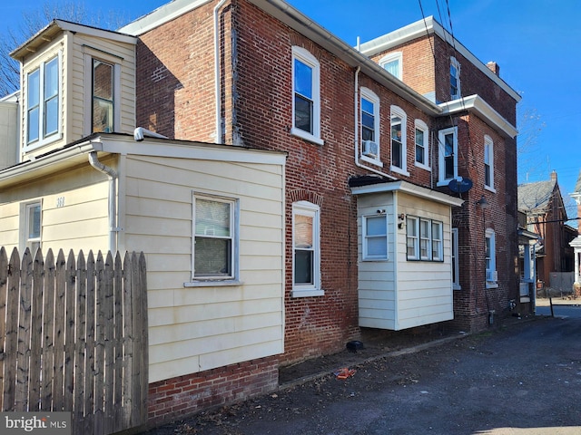 view of side of home with fence and brick siding