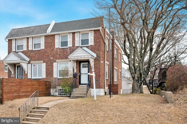 view of front facade featuring entry steps, brick siding, and roof with shingles