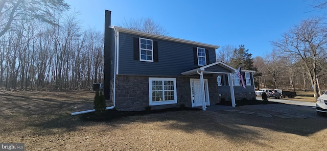 view of front of house with stone siding and a chimney